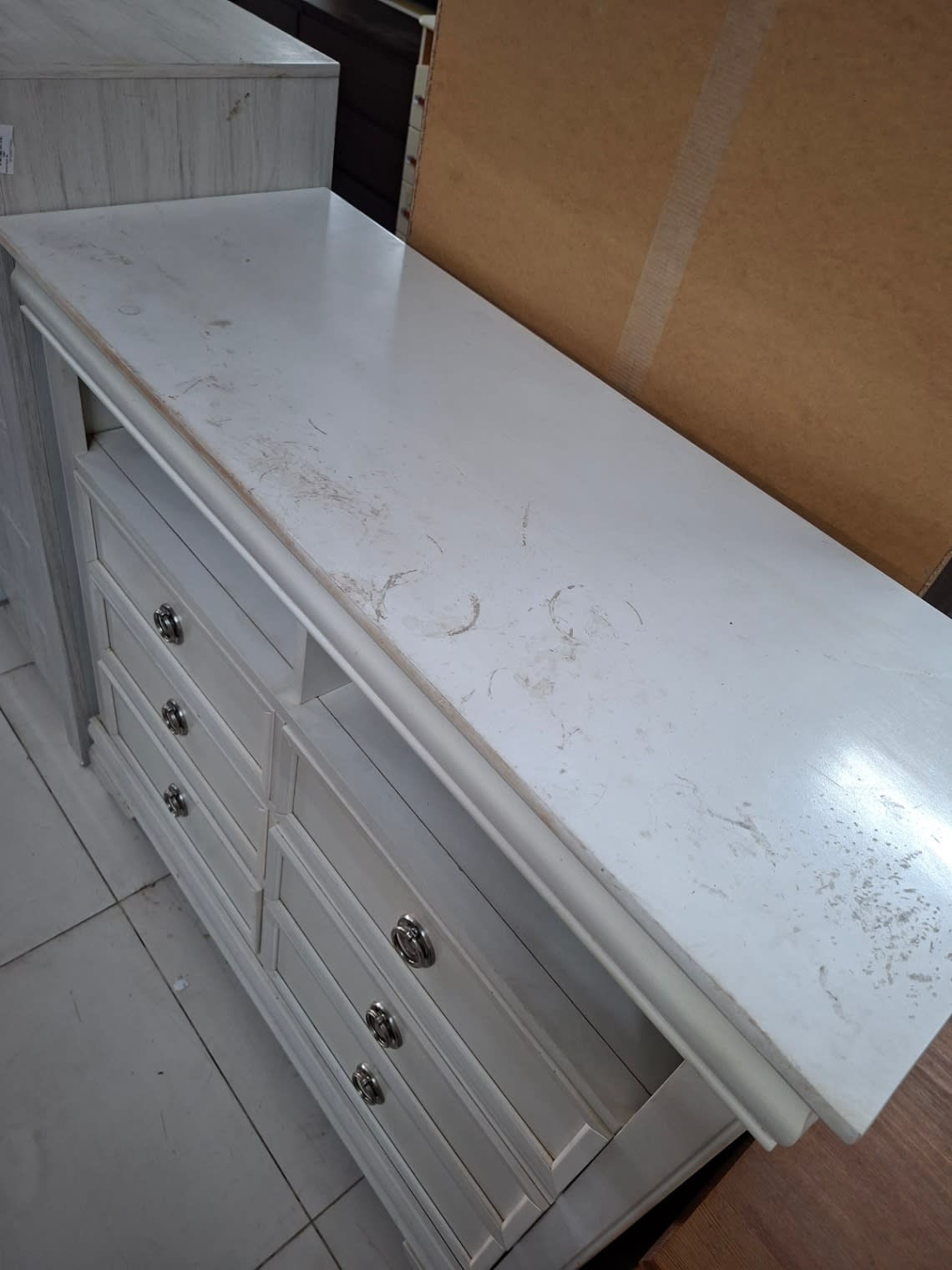 Top surface of used white chest of drawers showing visible scratches and scuff marks