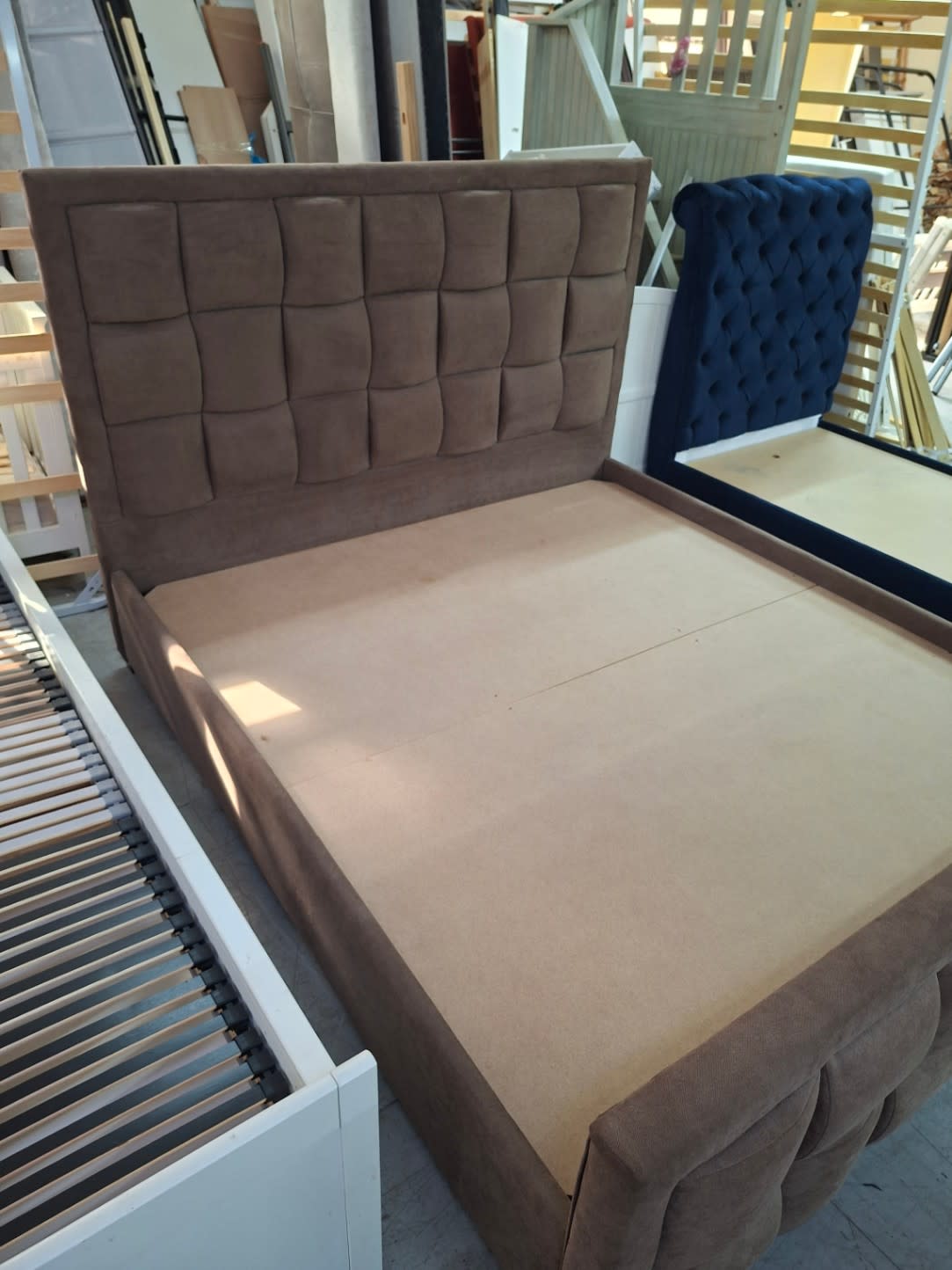 Side angle of used queen upholstered bed frame showing footboard and platform base
