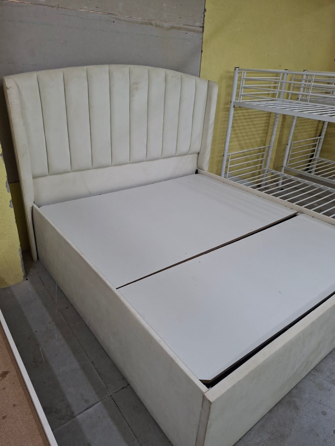 Side-angle view of used cream upholstered queen bed frame with storage at Shop C Bufaisal Ajman
