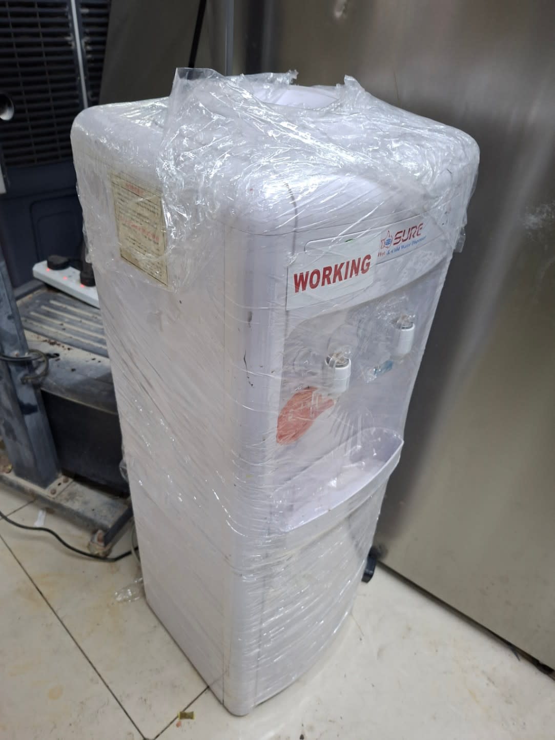 Full side view of used Sure hot and cold water dispenser in good condition at Shop C Ajman