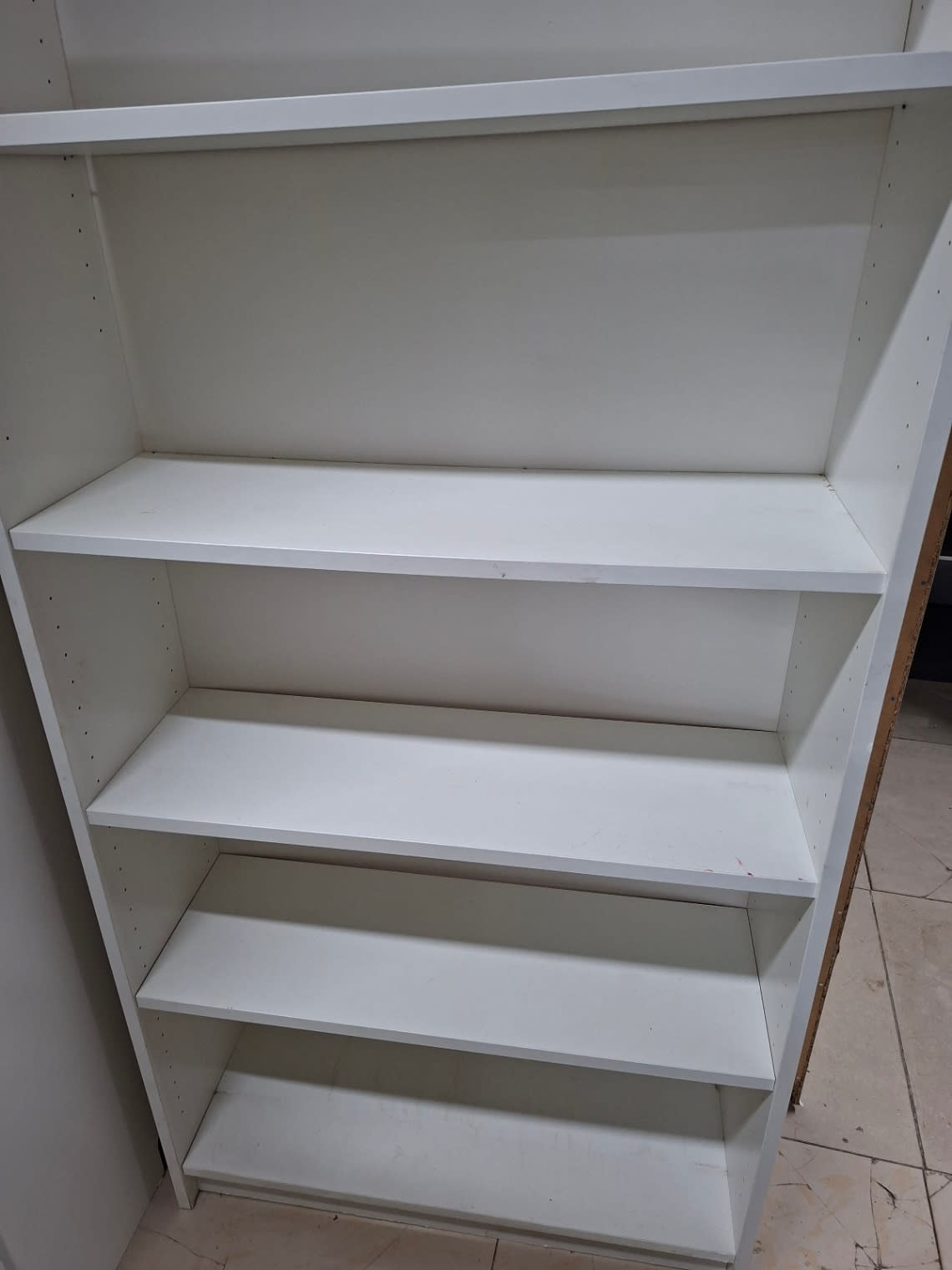 Close-up of lower shelves on used white shelving unit showing minor scuff marks and stain spots