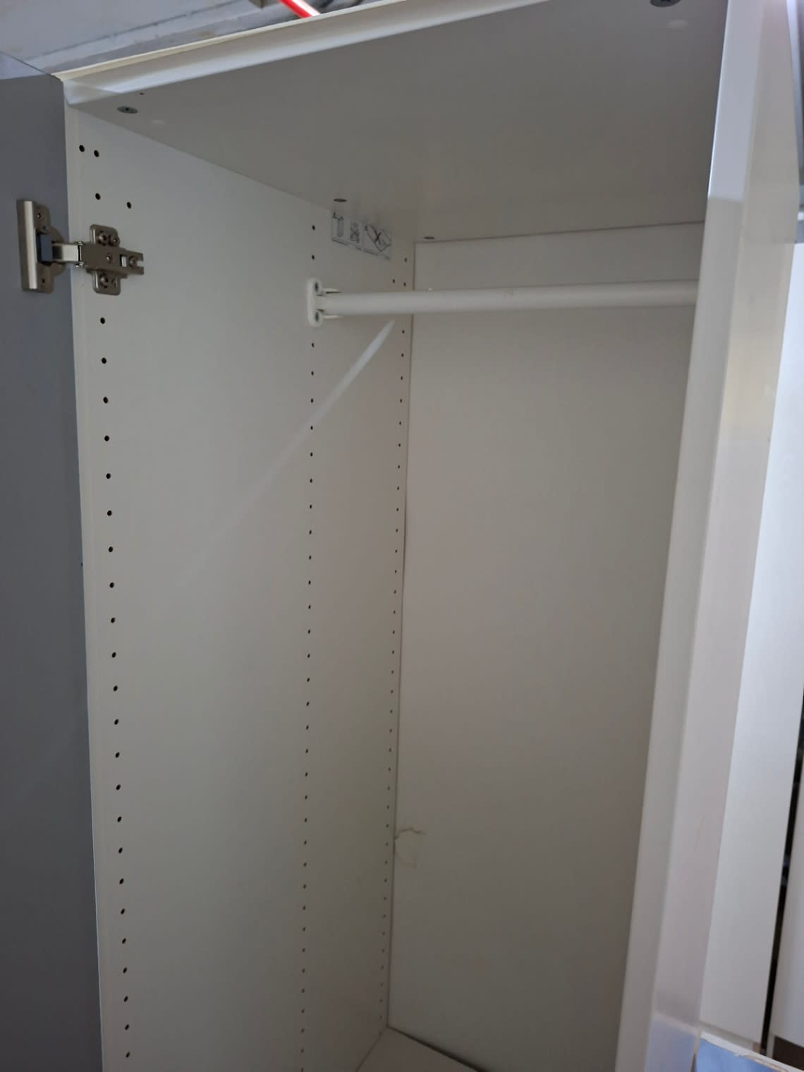 Top interior view of used white single-door wardrobe showing hanging rail and hinge at Bufaisal Ajman