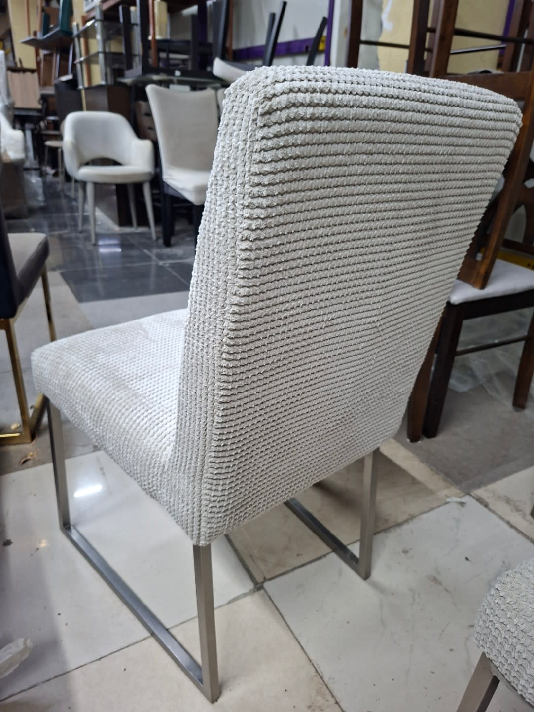 Rear view of new cream fabric dining chair with chrome base at Bufaisal Shop C Ajman