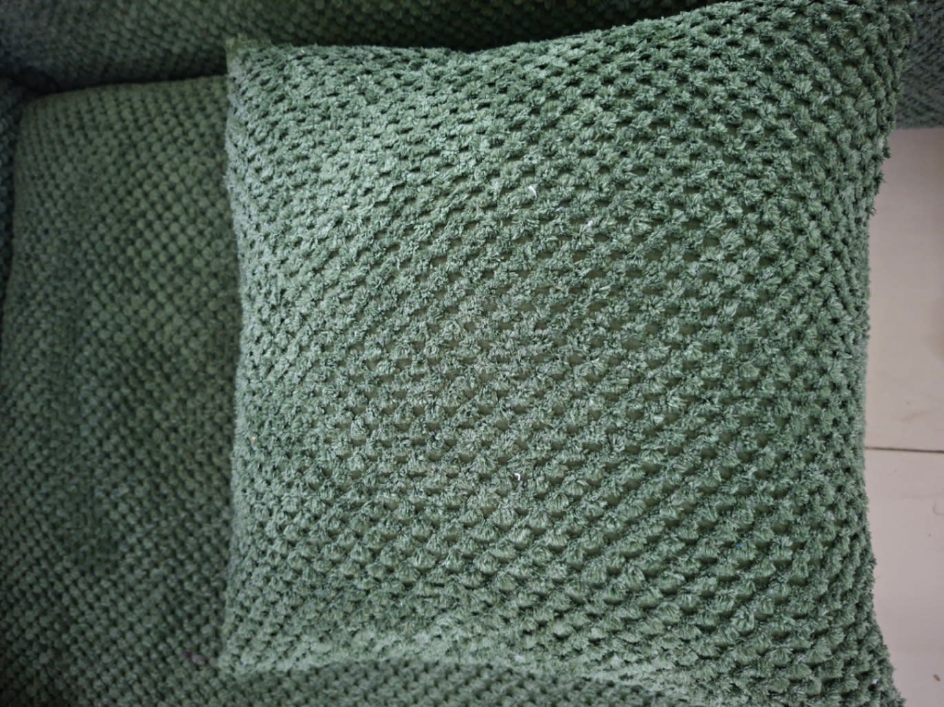 Close-up of green woven scatter cushion included with new L-shape sectional sofa at Bufaisal Ajman