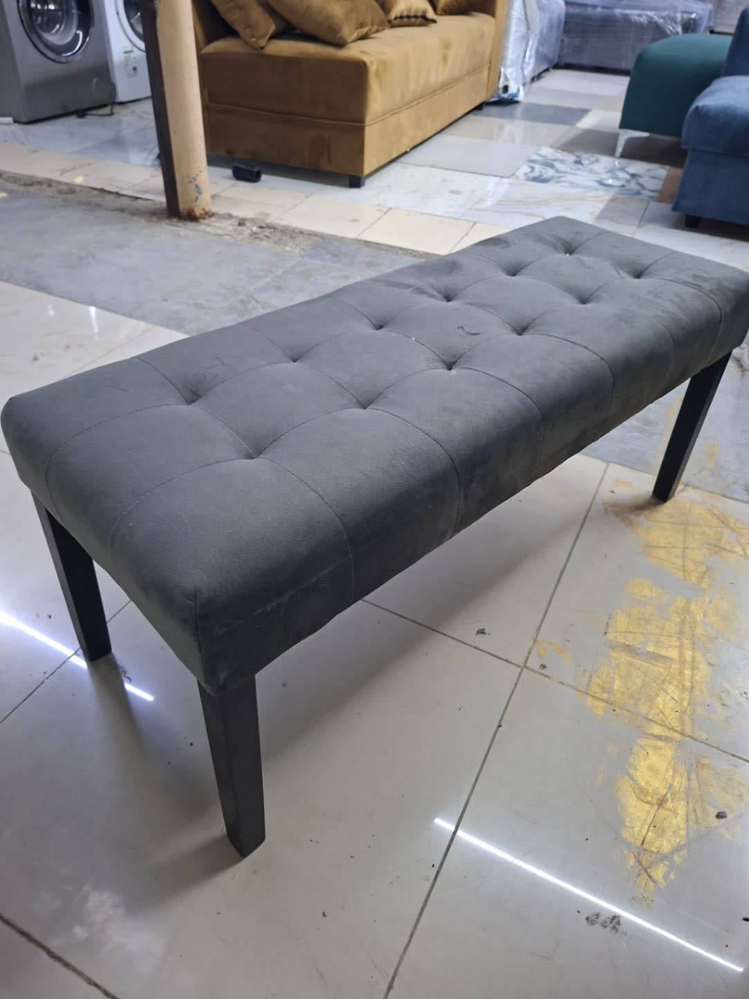 Additional angle of used grey tufted upholstered bench showing overall condition