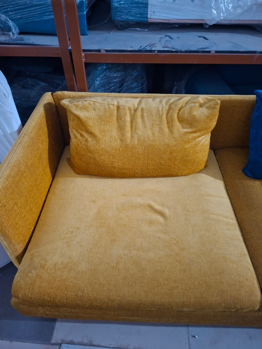 Side section detail of used mustard yellow 3-seater sofa showing cushion and armrest condition