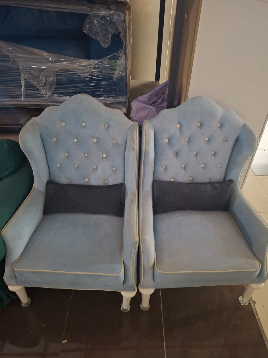 Front view of both used blue velvet wingback accent chairs showing seat condition at Bufaisal Ajman