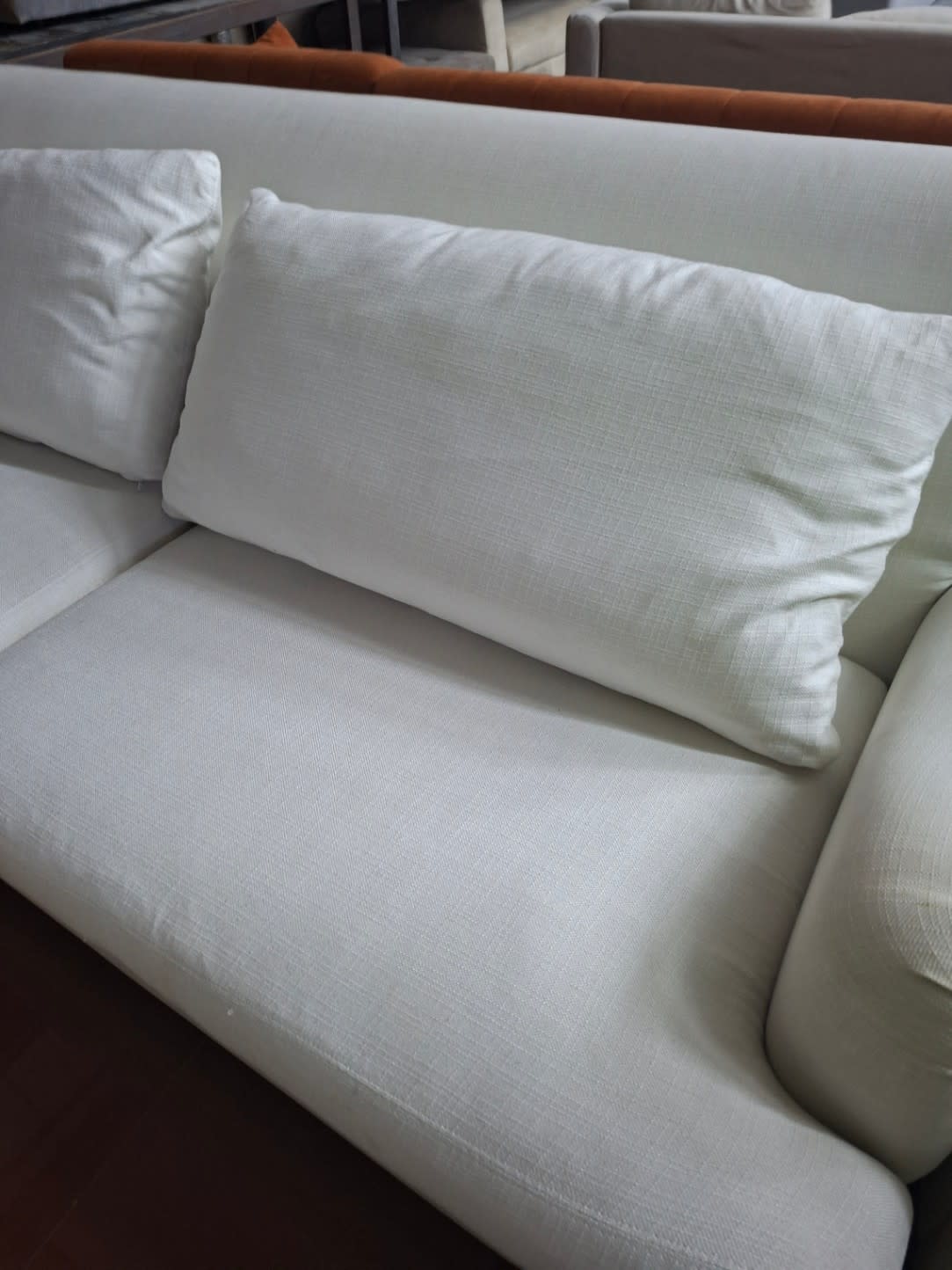 Close-up of used off-white sofa seat and cushions showing fabric texture and minor surface wear