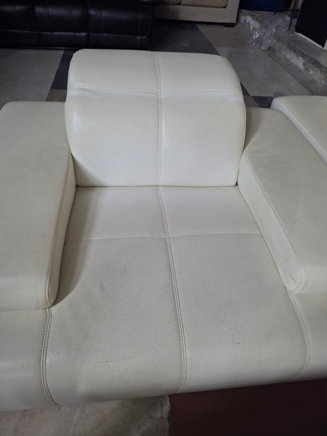 Seat cushion detail of used cream L-shape sectional sofa showing surface wear and condition