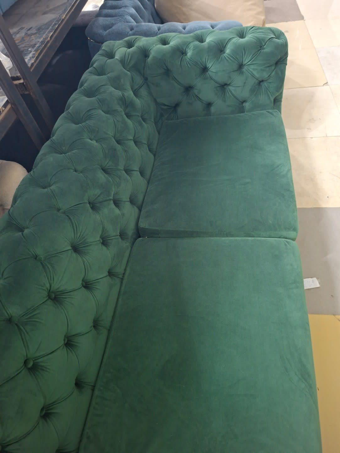 Top-down view of used green velvet Chesterfield sectional sofa showing L-shape configuration and seat surface