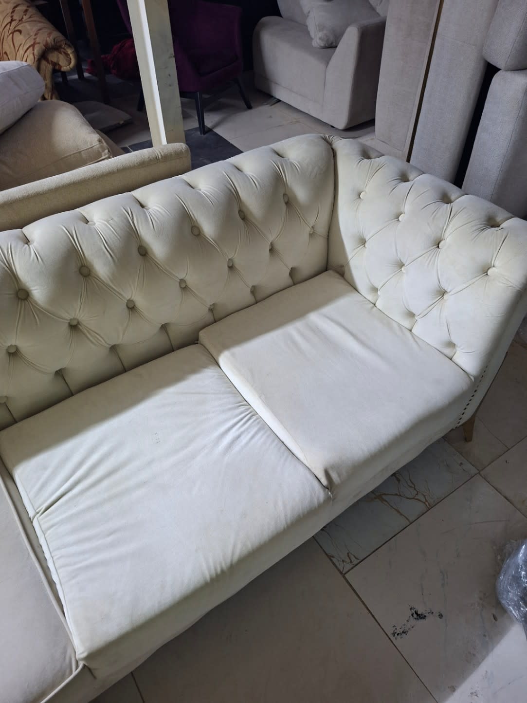 Second sofa unit from same set showing seat cushion wear on used cream Chesterfield sofa at Bufaisal Ajman
