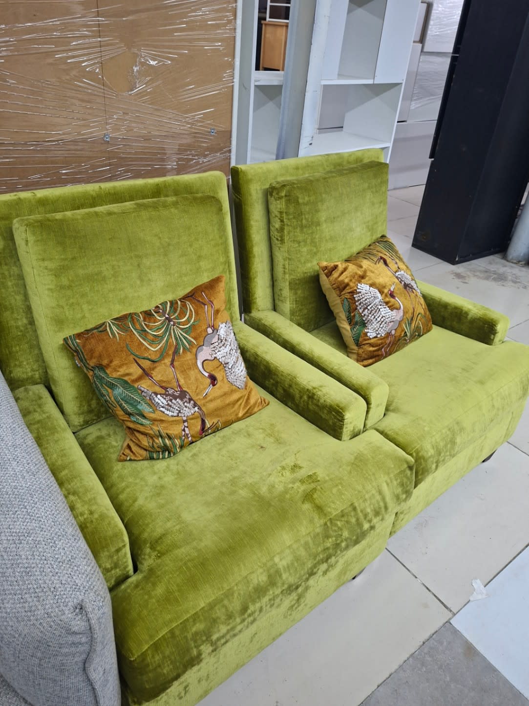 Front view of used green velvet armchair pair showing seat wear and decorative cushions at Bufaisal Ajman