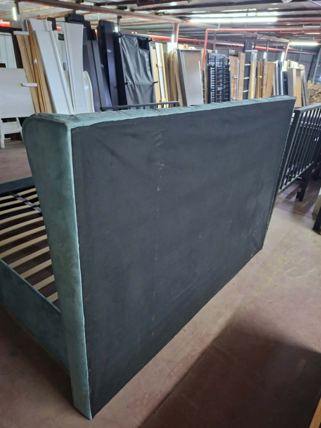 Back of headboard on used king tufted wingback bed frame showing scuff marks on dust liner fabric