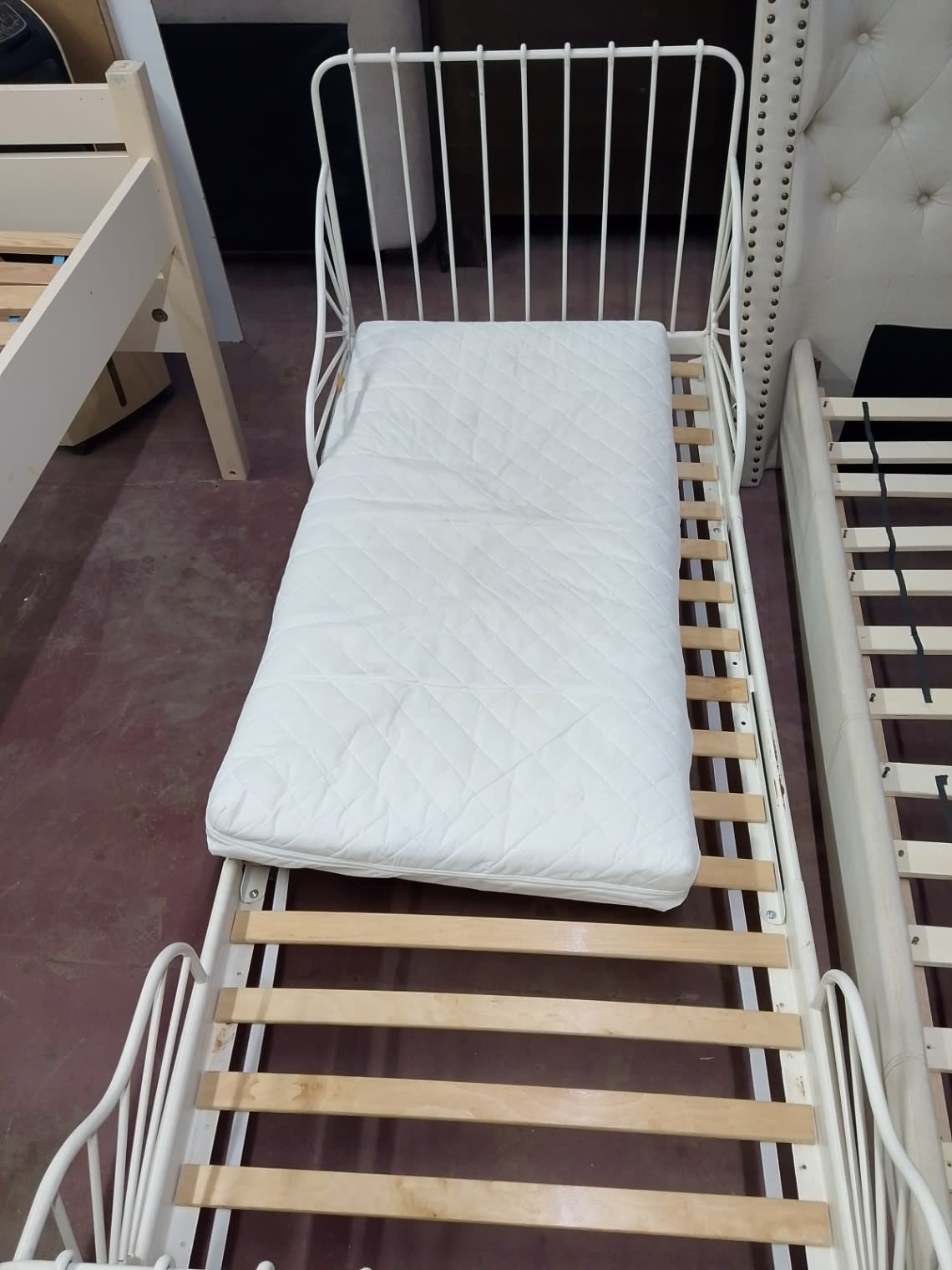 Overhead close-up of used IKEA kids extendable bed frame white showing mattress surface condition