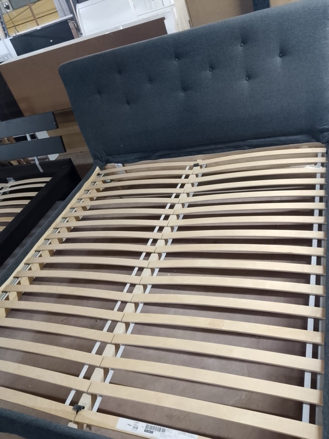 Bufaisal barcode label on used dark grey upholstered bed frame