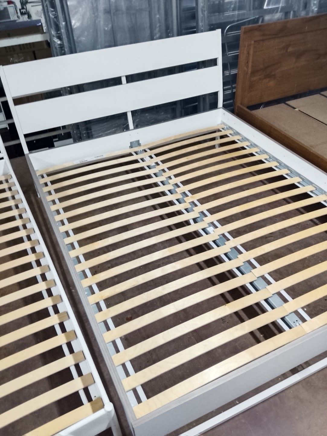 Top-down view of used white queen bed frame slatted base showing all slats intact