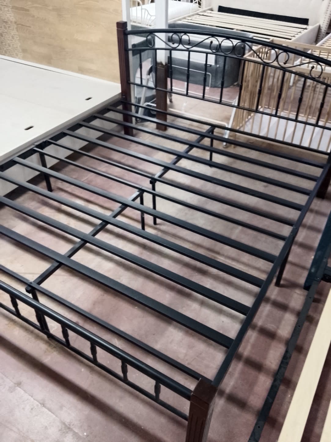 Close-up of metal slat platform and centre support leg on used black metal bed frame
