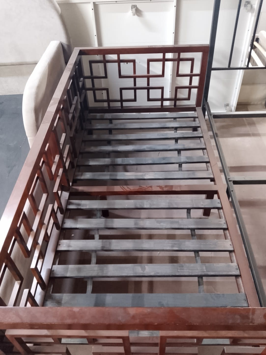 Top-down view of used single bed frame interior showing metal slat system and walnut wood frame