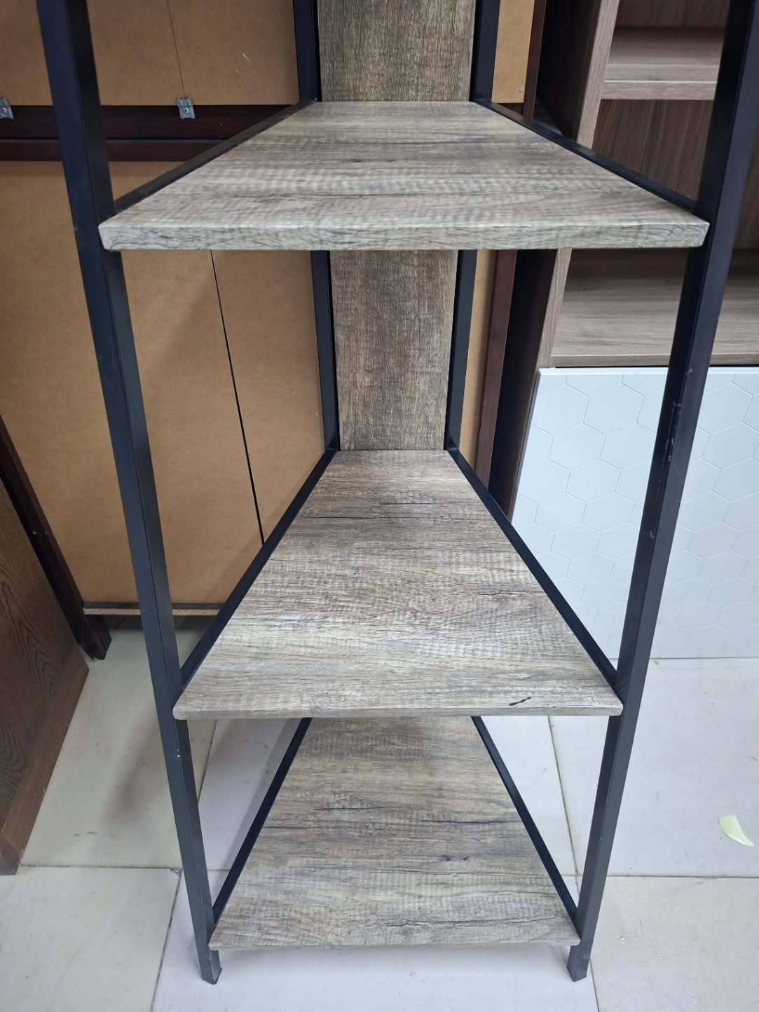 Close-up of lower shelves on used 5-tier ladder shelving unit showing minor surface wear and small edge chip