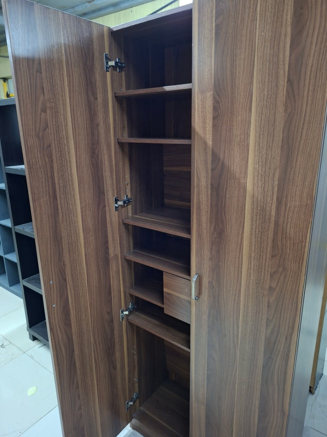 Side angle of used 2-door walnut brown storage cabinet open showing full interior shelving