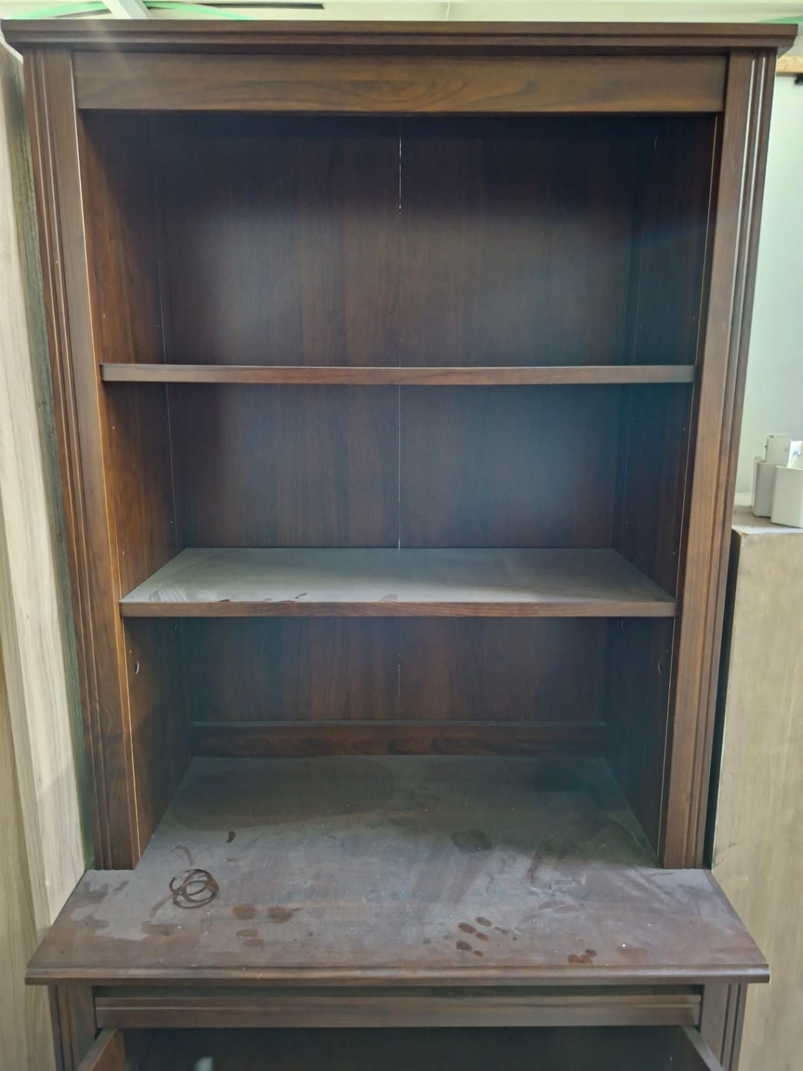 Close-up of open shelf section and cabinet top showing stains on used dark brown bookshelf