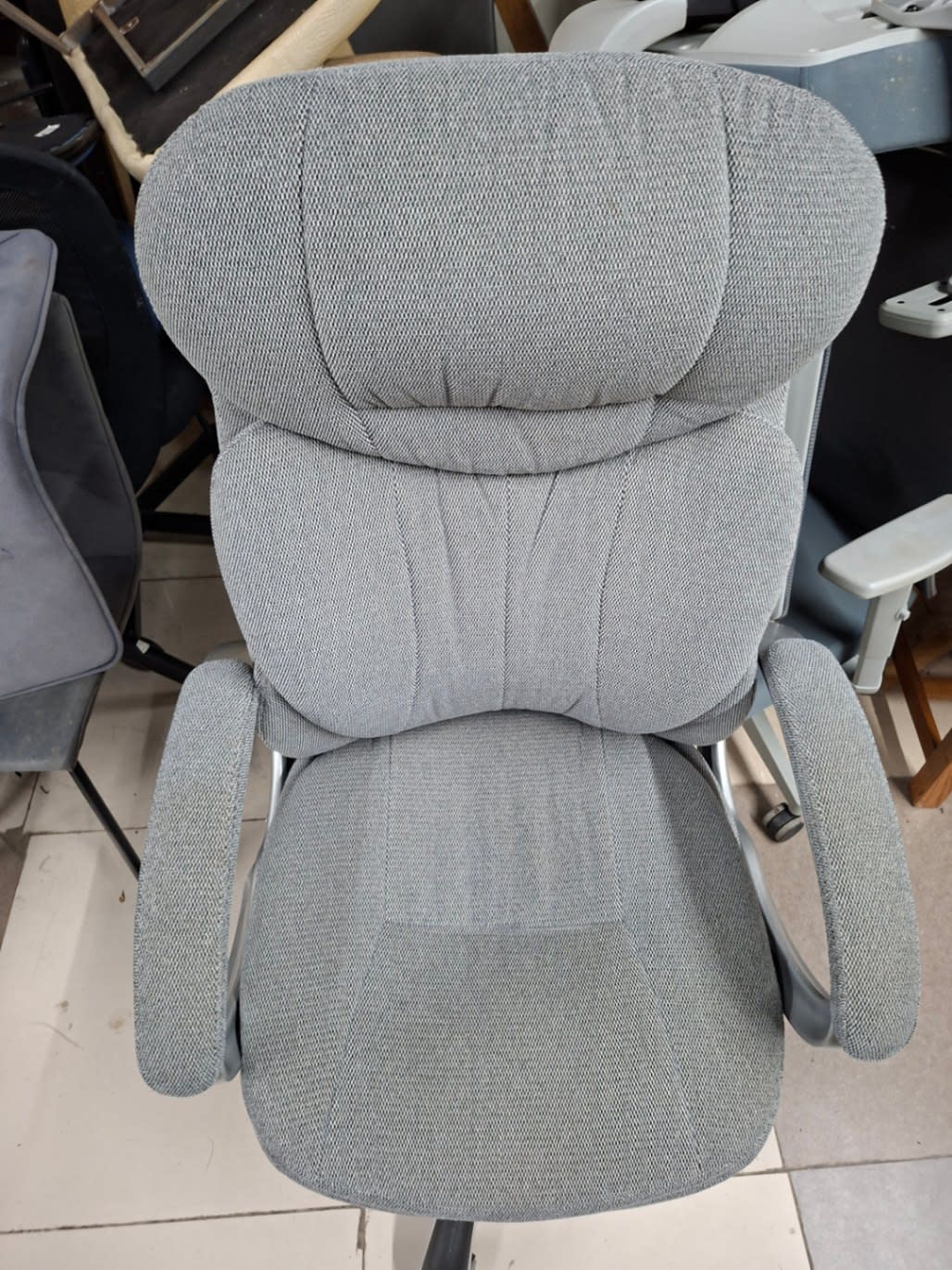 Top-down view of used grey high-back fabric office chair seat and backrest at Bufaisal Ajman