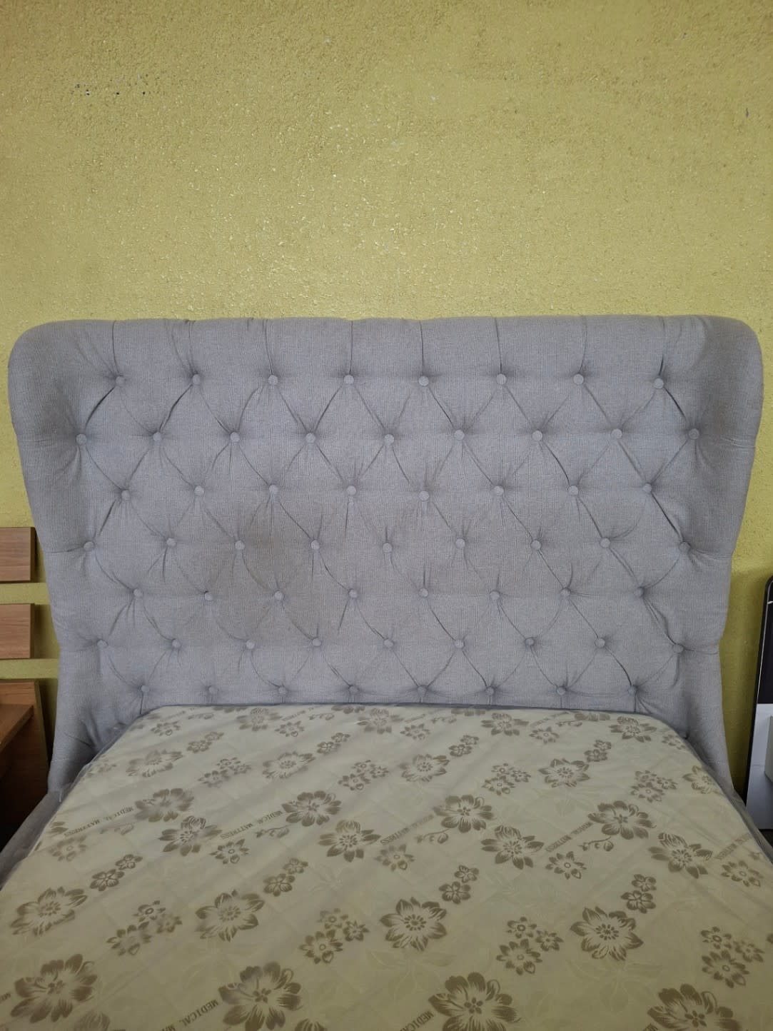 Close-up of grey button-tufted wingback headboard fabric on used bed frame at Bufaisal Shop C Ajman