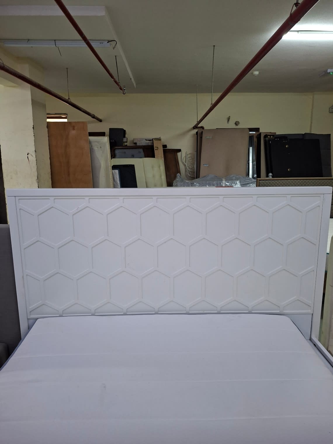 Close-up of honeycomb geometric headboard on used white queen bed frame at Bufaisal Shop C Ajman