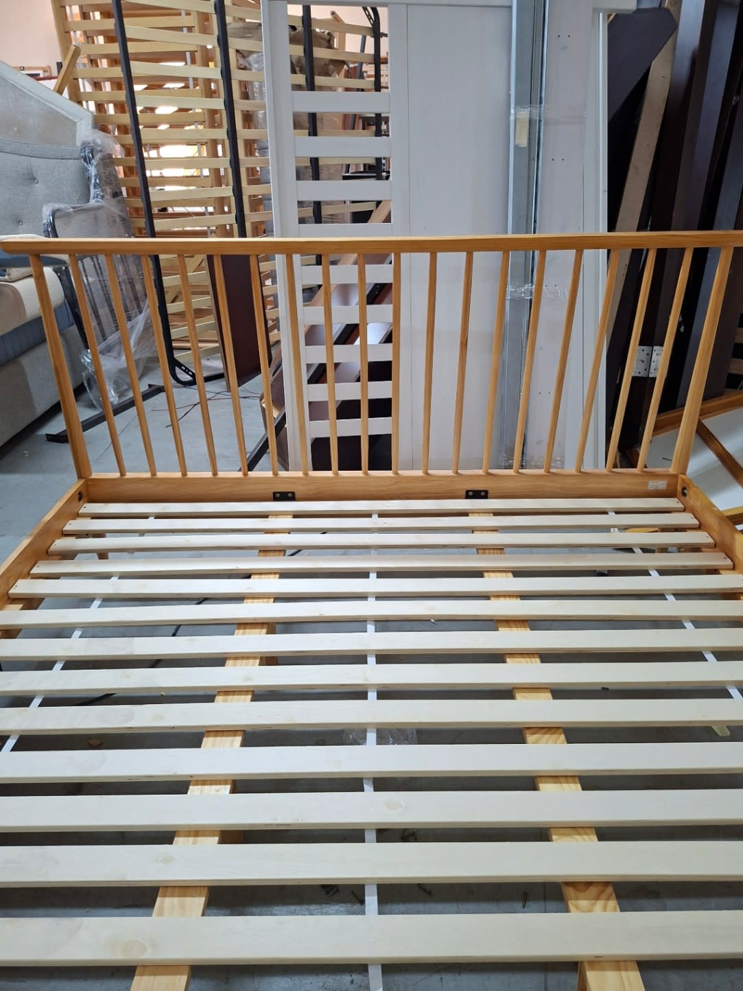Close-up of spindle headboard and slatted base on used wooden queen bed frame at Bufaisal Ajman