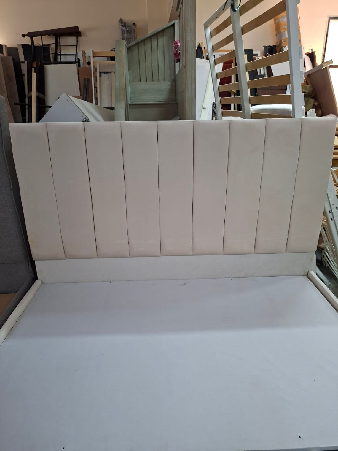 Close-up of channel-tufted headboard on used cream upholstered bed frame at Shop C Ajman