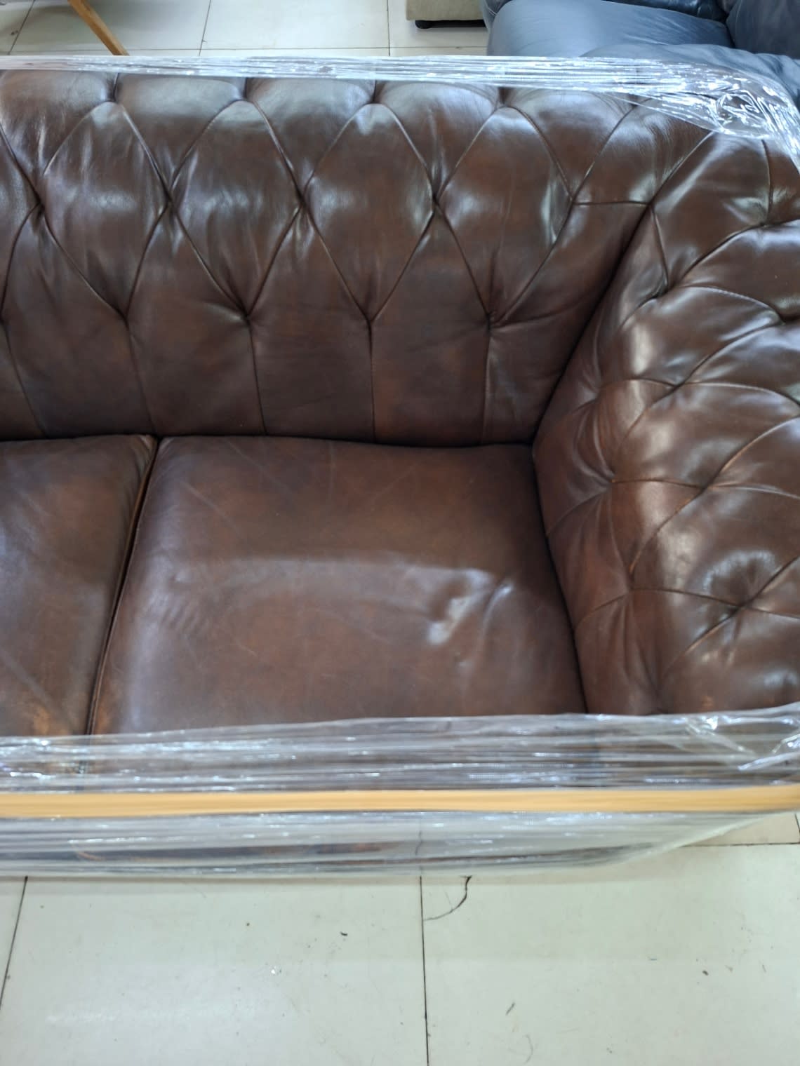 Detail of armrest and seat cushion of used brown Chesterfield 2-seater sofa at Bufaisal Ajman