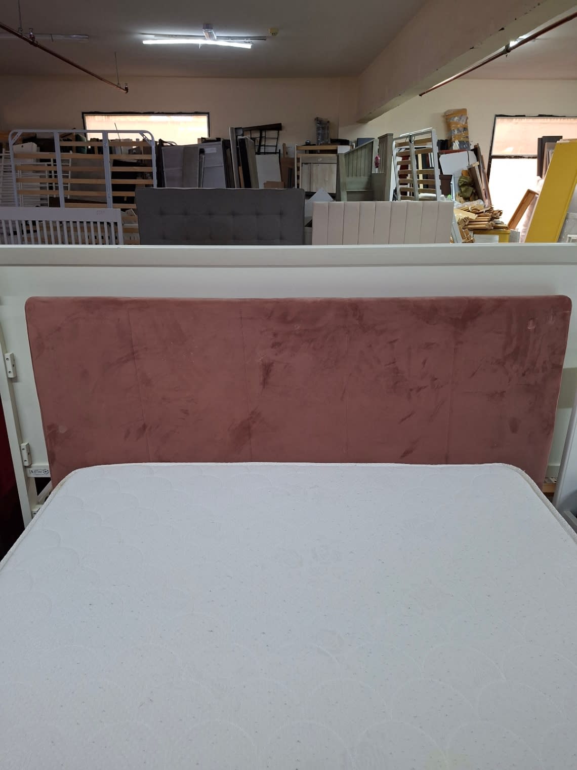 Close-up of pink velvet headboard on used queen bed frame showing surface wear at Bufaisal Ajman