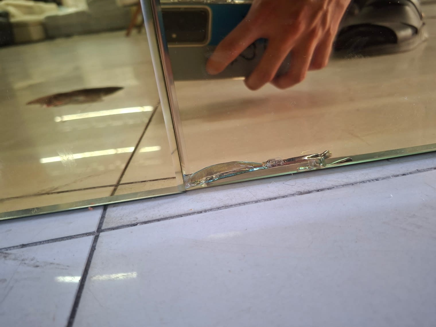Close-up of chipped and cracked corner on gold mirror panel of used electric fireplace TV stand