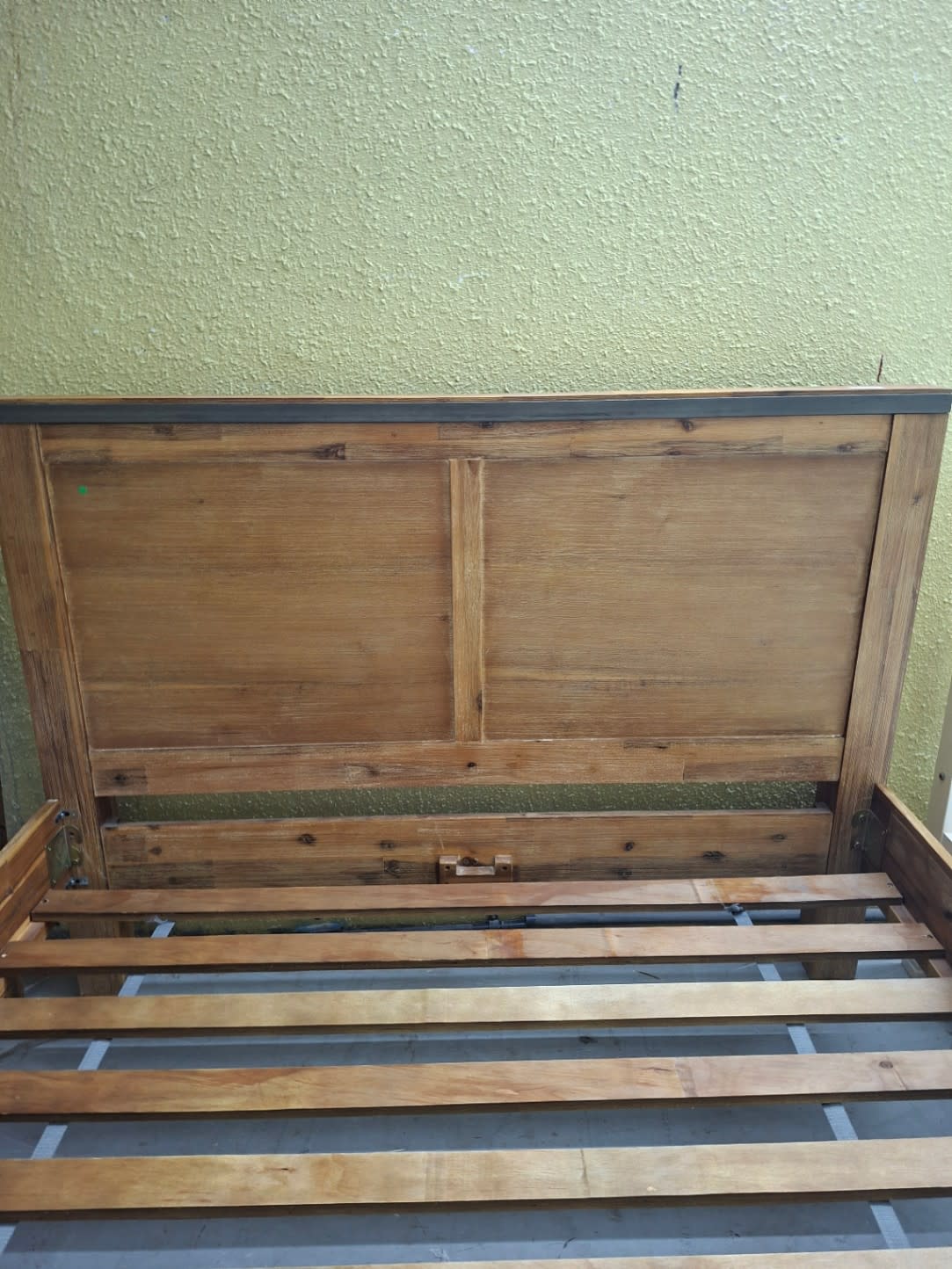 Close-up of headboard detail on used wooden queen bed frame showing natural wood grain
