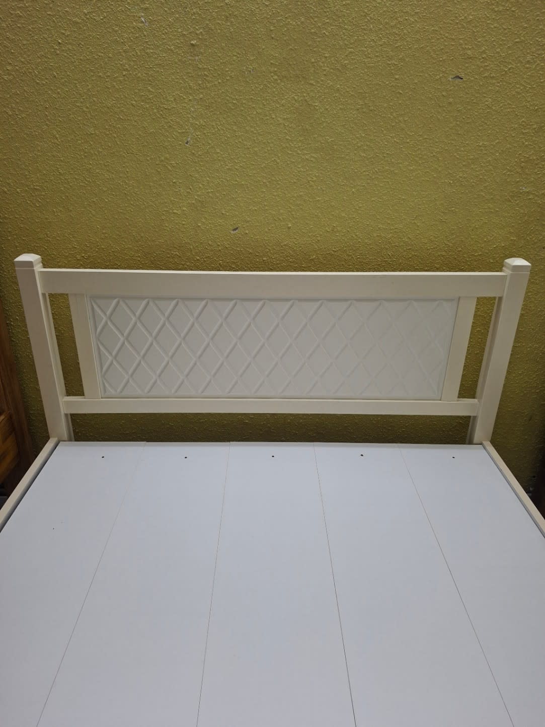 Close-up of diamond lattice embossed headboard on used white queen bed frame at Bufaisal Ajman