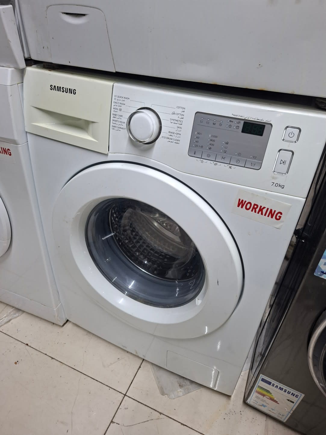 Side view of used Samsung 7kg front-load washing machine with WORKING sticker at Shop C Ajman