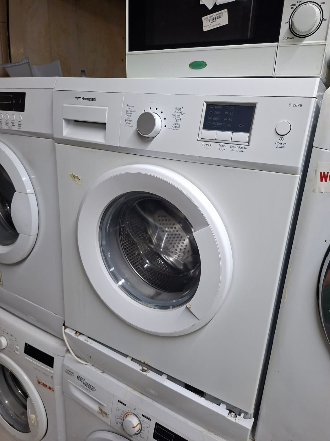 Full front view of used Bompani BI2876 front-load washing machine showing base rust and sticker residue