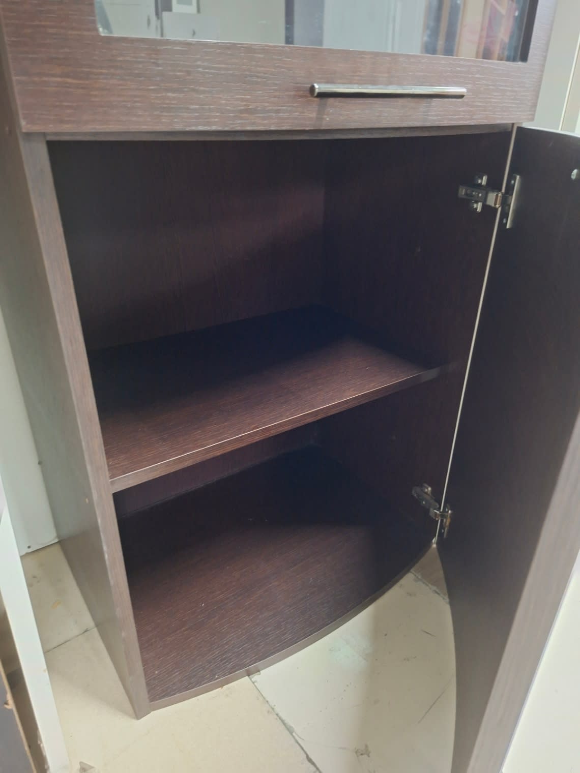 Lower section of used tall dark walnut display cabinet open showing two wood shelves