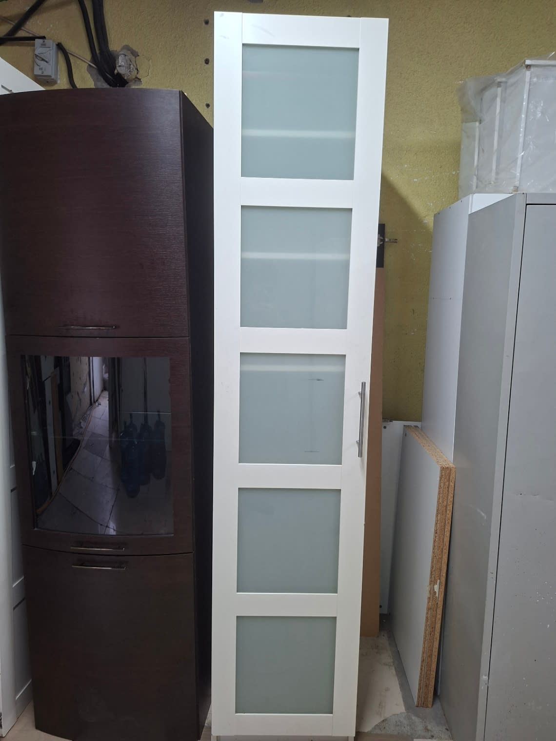 Full exterior view of used tall white storage cabinet with 6-panel frosted glass door and silver handle at Bufaisal Ajman