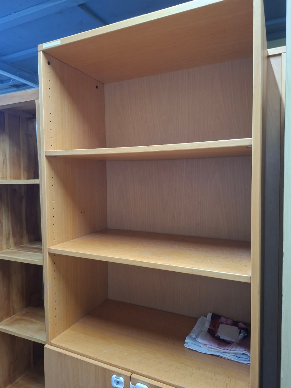 Side angle of used beech bookcase showing open shelves and two-door lower cabinet at Bufaisal Ajman