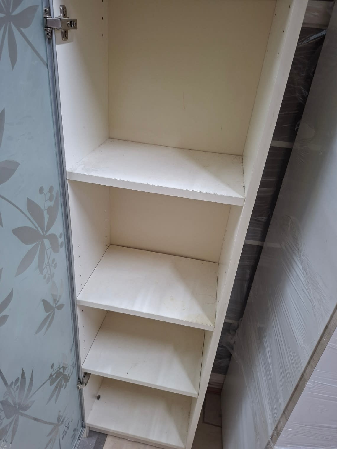 Interior shelves of used single-door storage cabinet showing light surface scratches