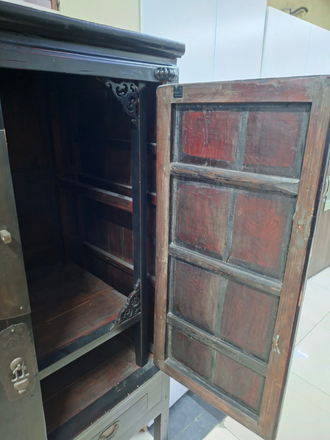 Side view of used Chinese antique wooden cabinet with door open showing interior panel condition
