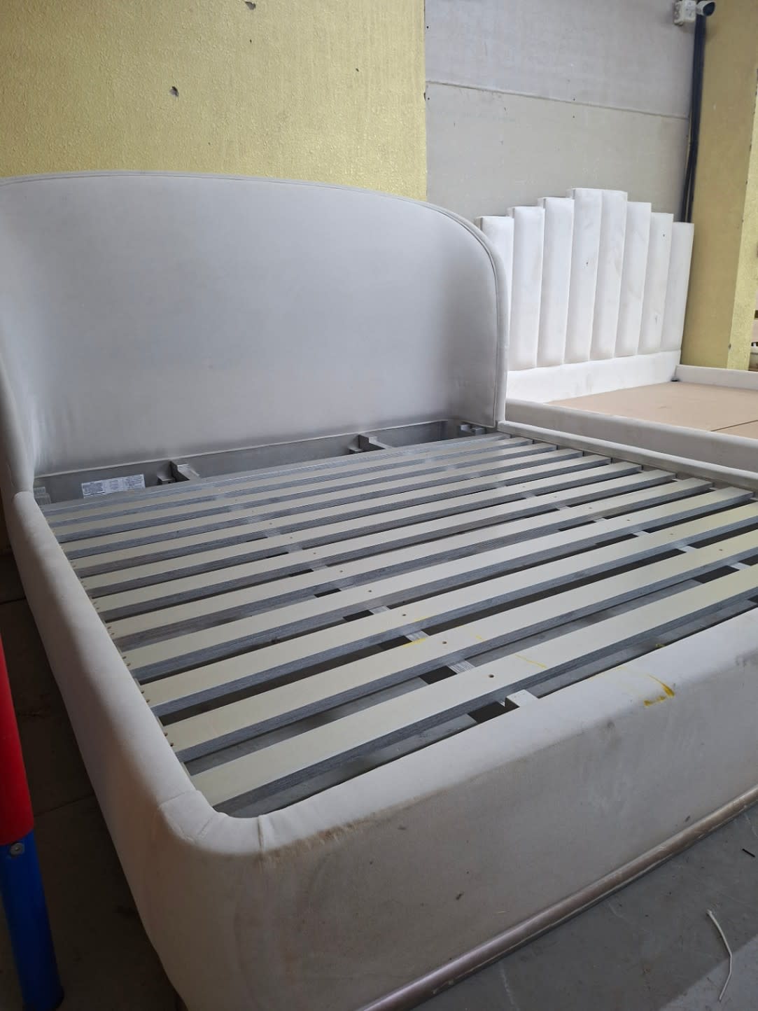 Lower front corner of used white queen bed frame showing visible staining on base panel