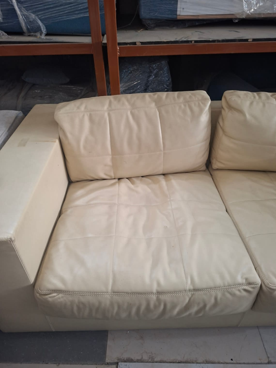 Close-up of used cream leather sofa seat showing minor surface scuffs and cushion wear