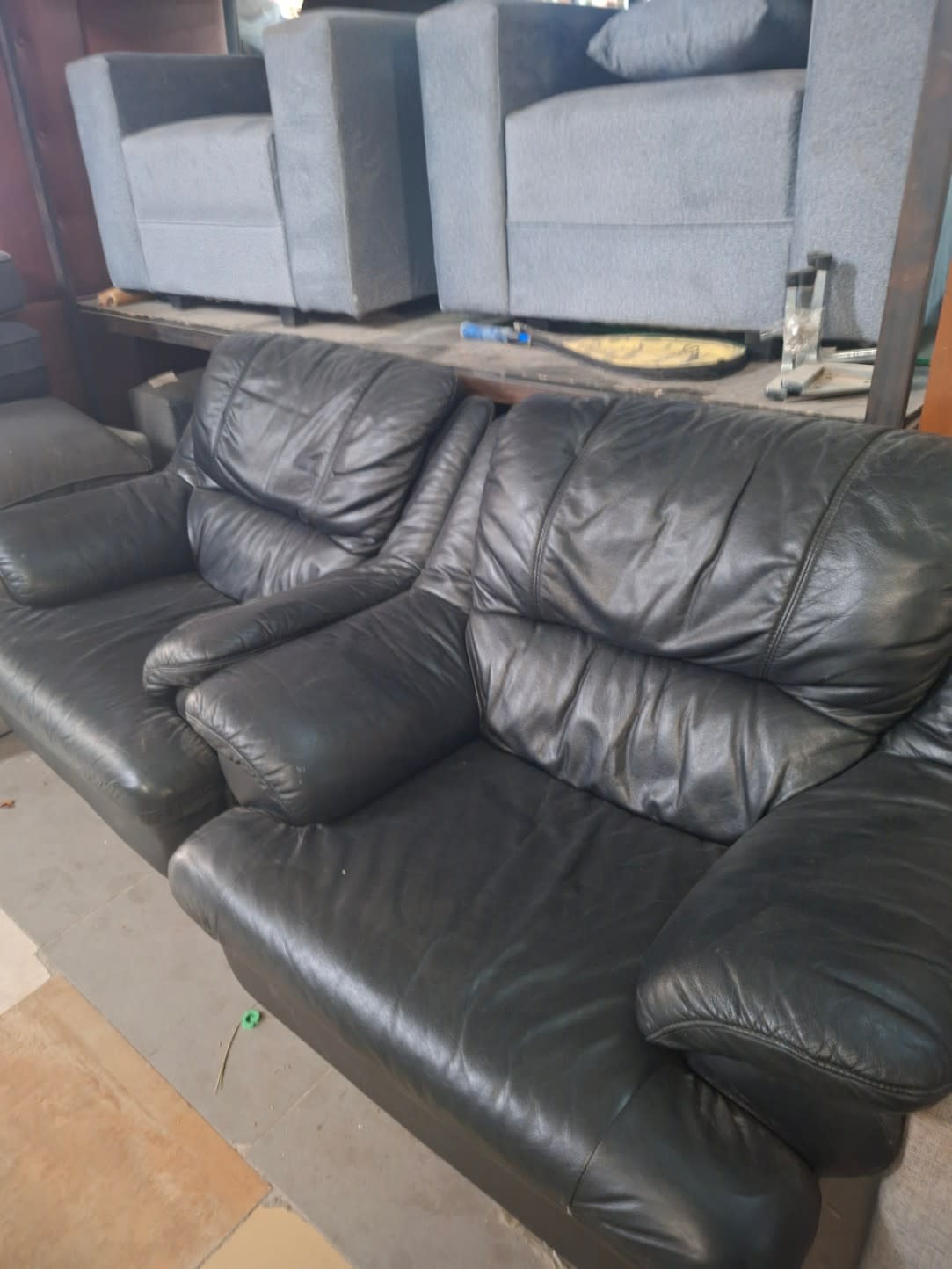 Side angle of used black leather 3-seater sofa showing upholstery condition at Bufaisal Ajman
