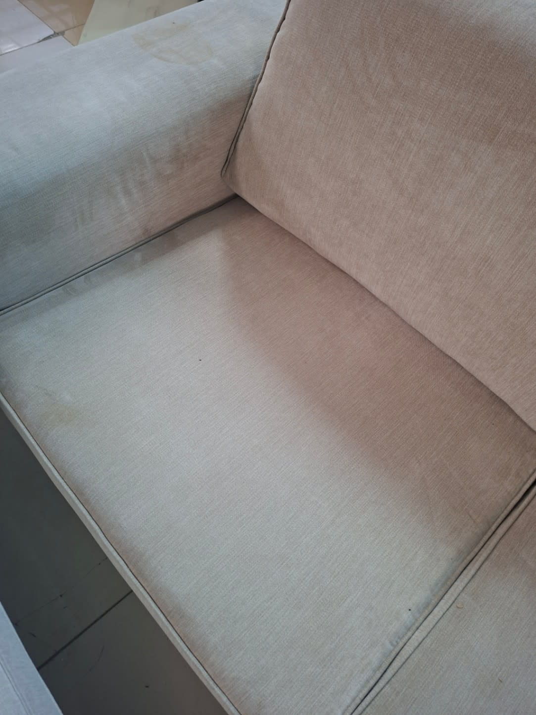 Seat surface detail of used beige fabric sofa showing visible staining and wear