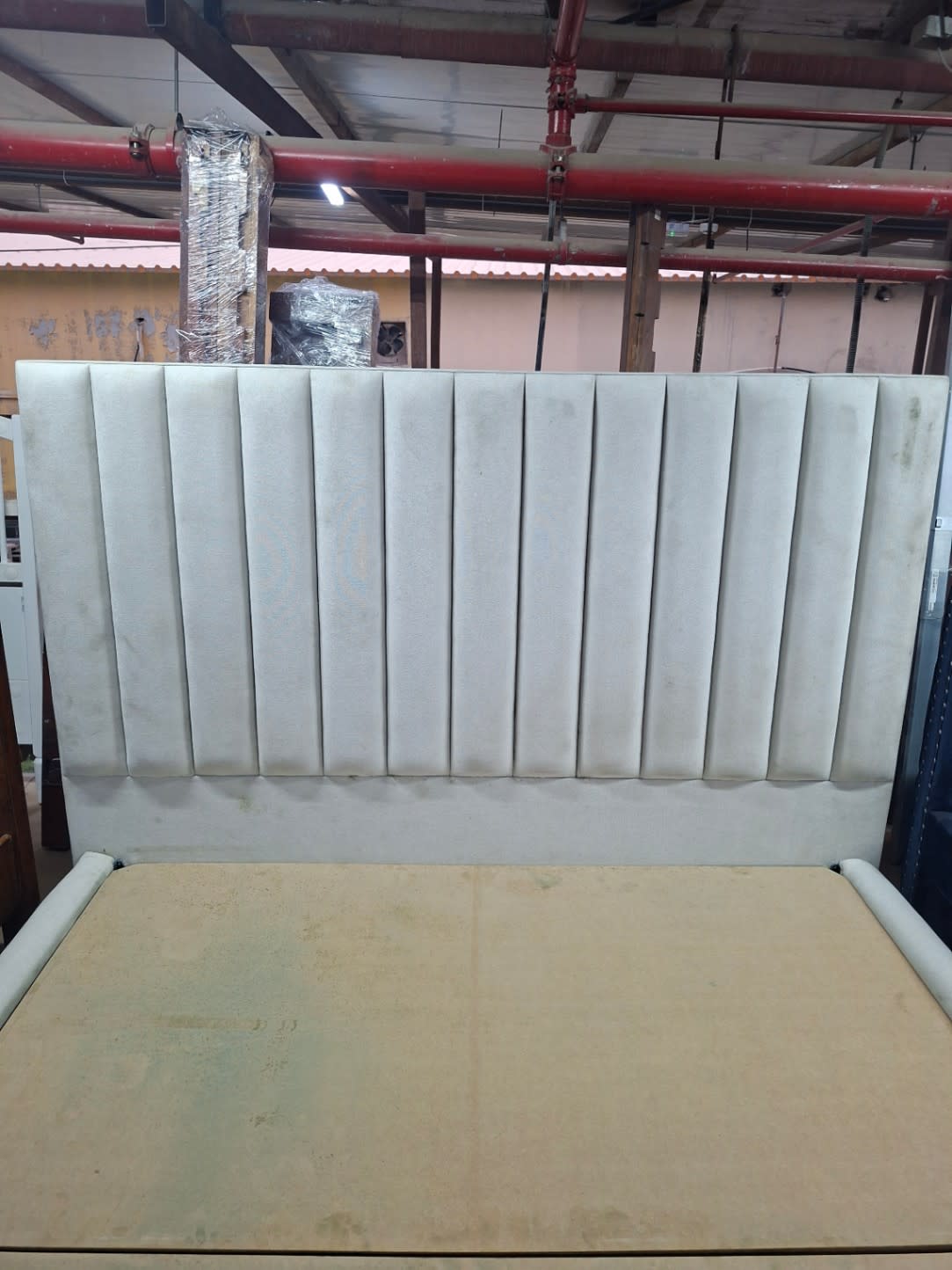 Close-up of channel-tufted headboard on used grey upholstered bed frame at Bufaisal Shop D Ajman