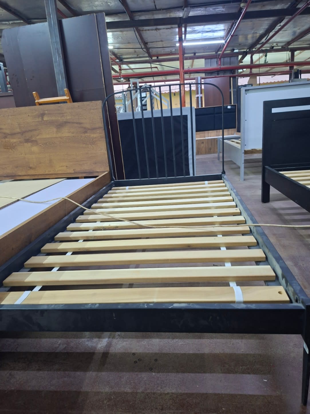 Full length view of used single metal bed frame dark grey showing slatted base and headboard