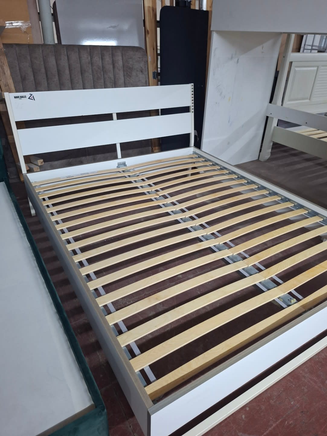 Side angle of used white queen bed frame showing slatted base and frame structure at Bufaisal Shop D Ajman