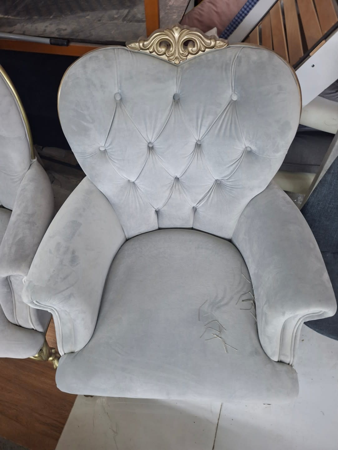 Top-down view of used grey velvet tufted armchair seat showing fabric snag marks on cushion